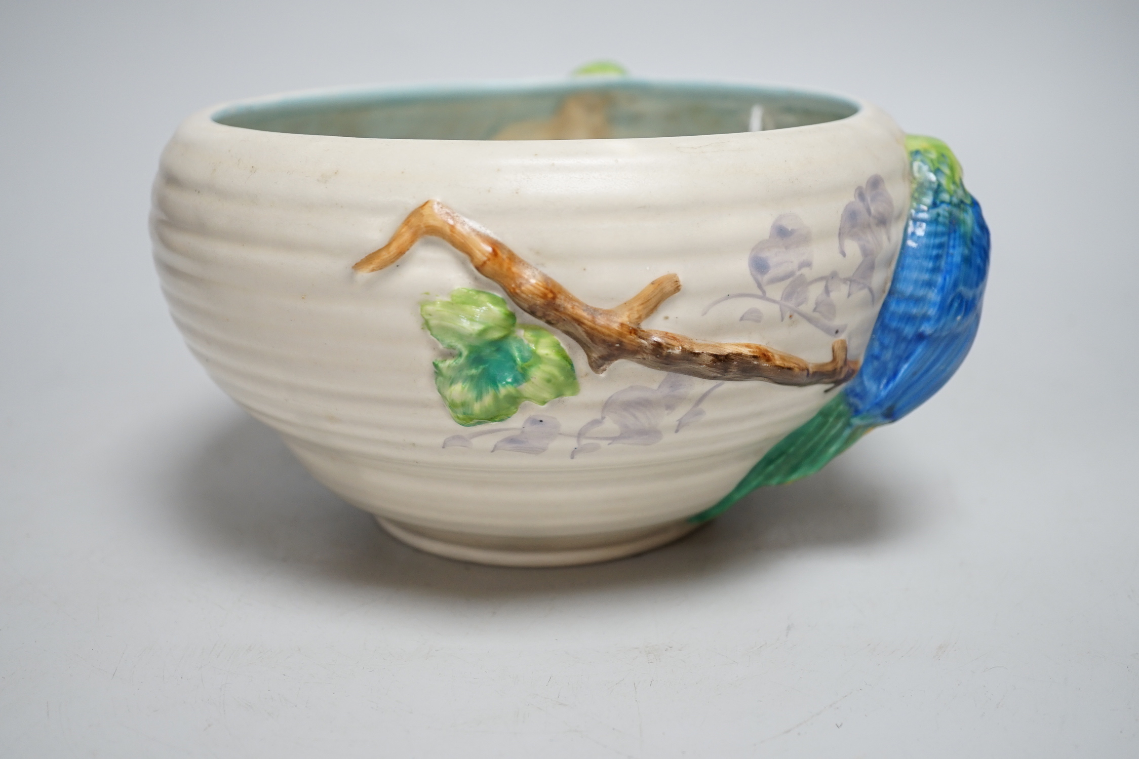 A late Clarice Cliff bowl with perched parrot decoration, 12cm tall